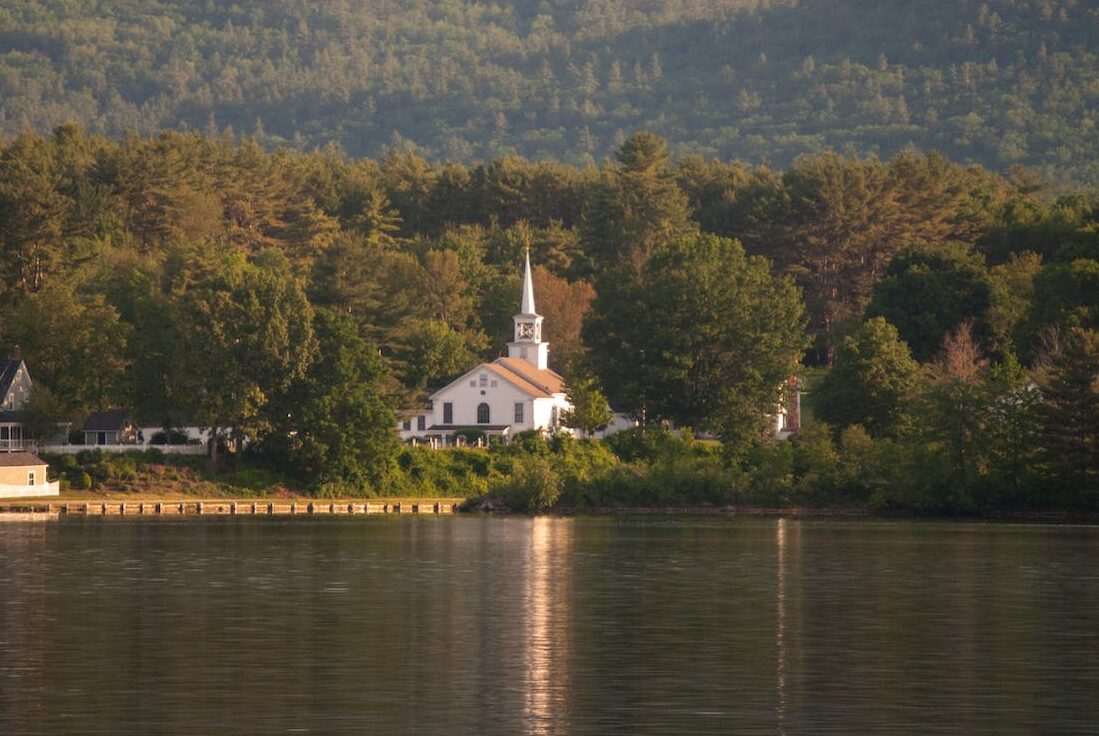 white church building near the mountain representing free consultations provided to boat accident victims across new hampshire
